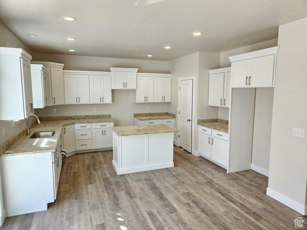 Kitchen featuring white cabinets, light hardwood / wood-style flooring, sink, and a kitchen island