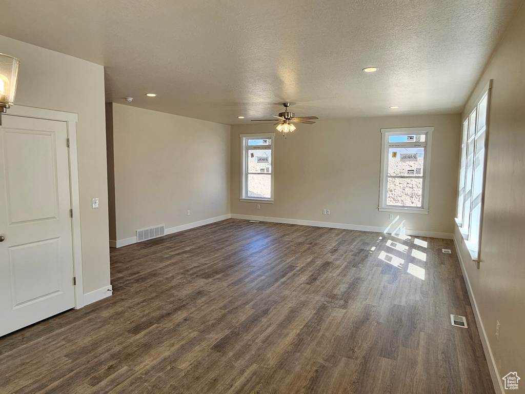 Spare room featuring ceiling fan, dark hardwood / wood-style floors, and a textured ceiling