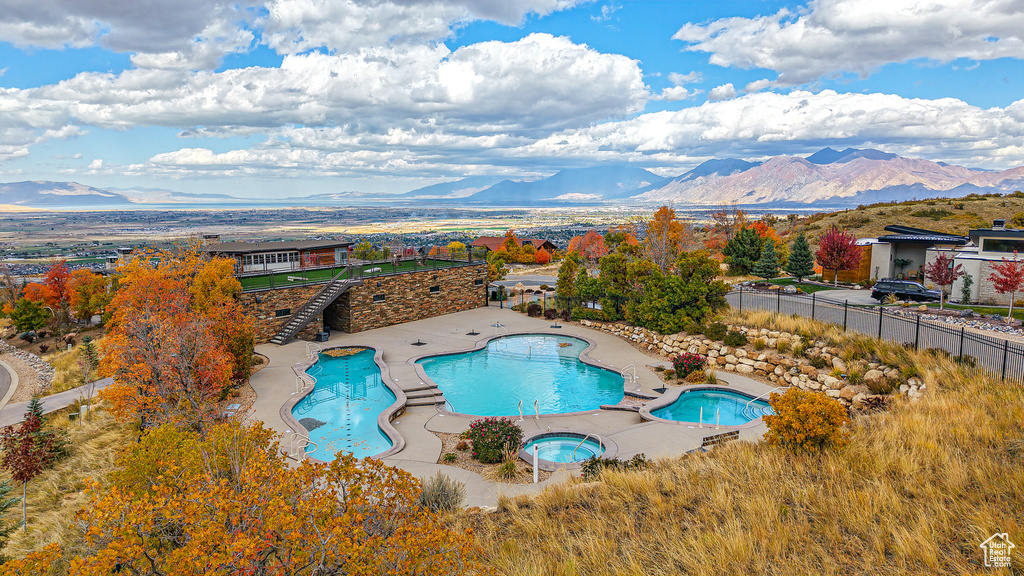 View of pool featuring a hot tub, a patio area, and a mountain view