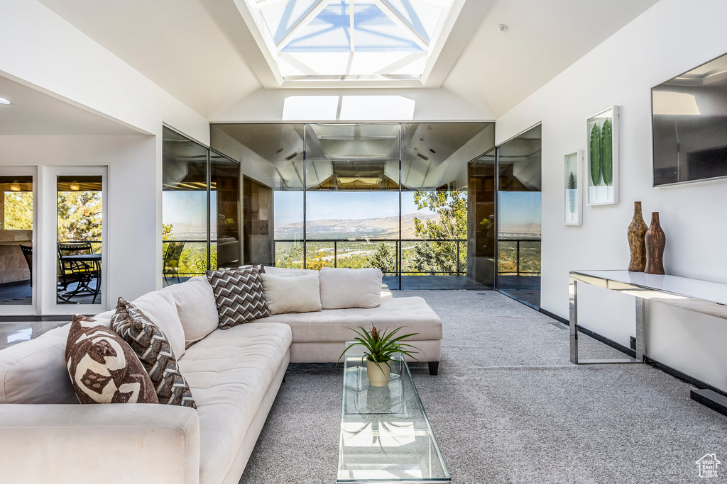 Carpeted living room featuring lofted ceiling with skylight