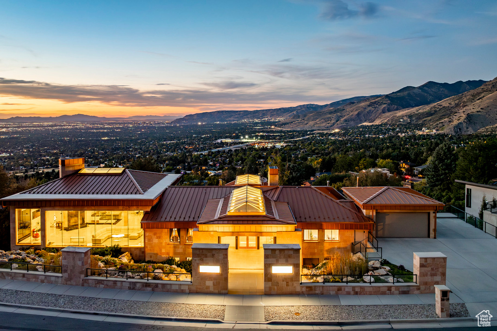 View of front facade with a chimney, a standing seam roof, a mountain view, concrete driveway, and metal roof
