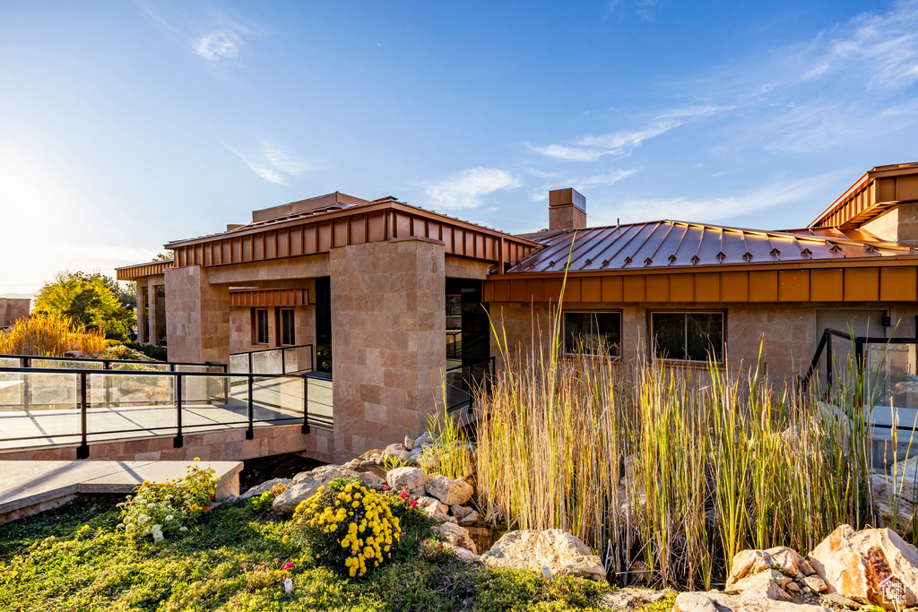 View of front of property featuring a standing seam roof, a chimney, and metal roof