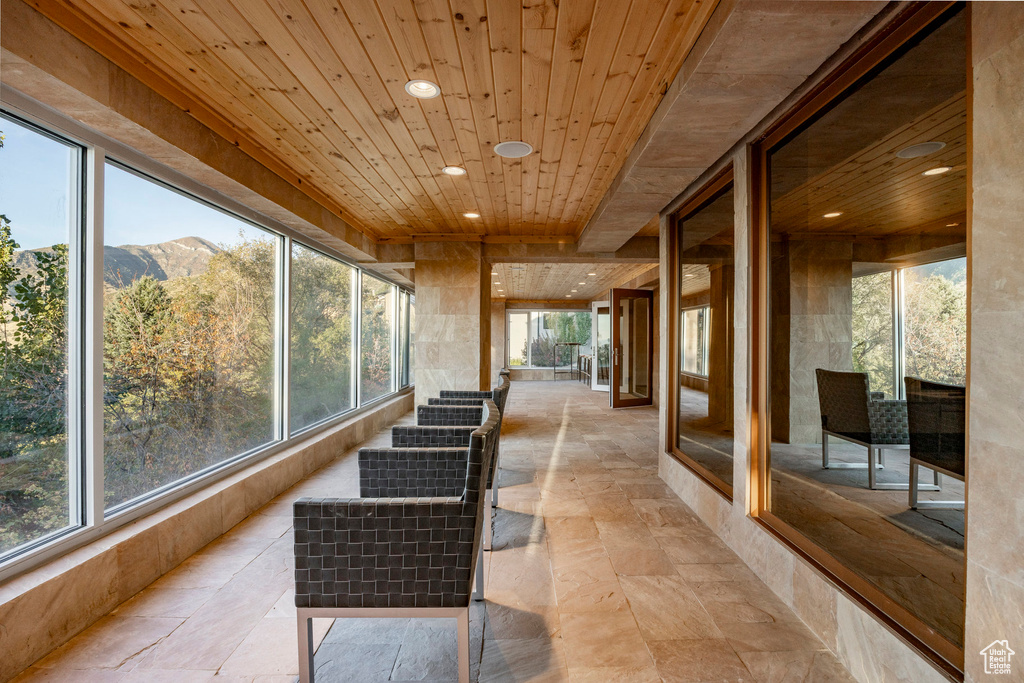 Sunroom featuring a mountain view, plenty of natural light, and wood ceiling