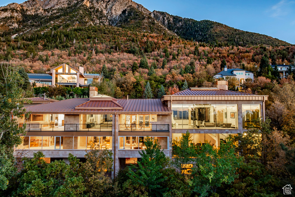Rear view of property featuring a balcony, a chimney, metal roof, a standing seam roof, and a mountain view
