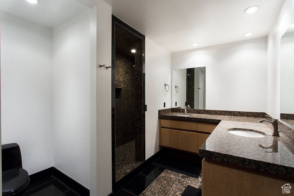 Bathroom with tile patterned flooring, a tile shower, vanity, and toilet