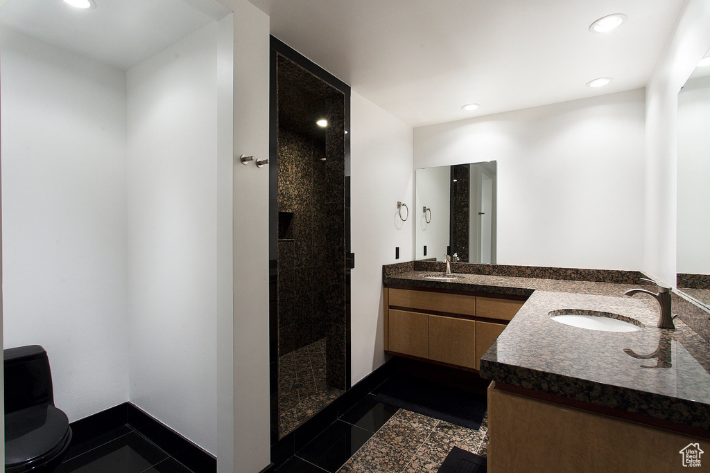 Bathroom featuring vanity, tiled shower, toilet, recessed lighting, and baseboards