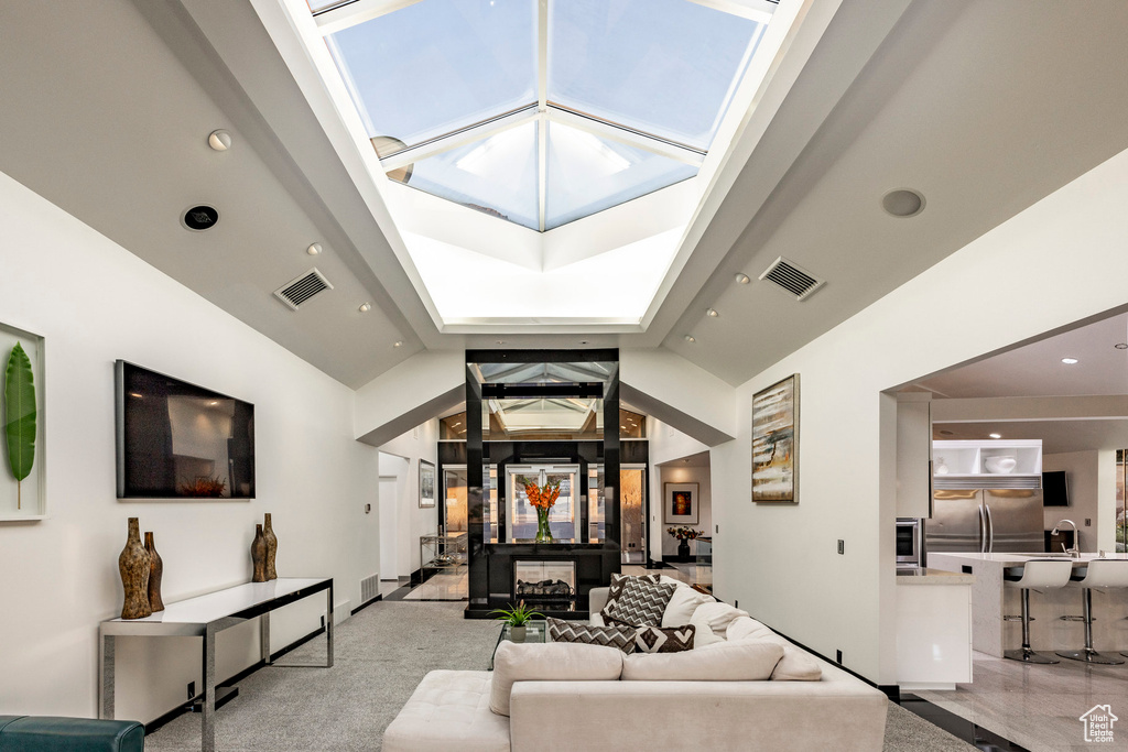 Living area featuring high vaulted ceiling, recessed lighting, and a skylight