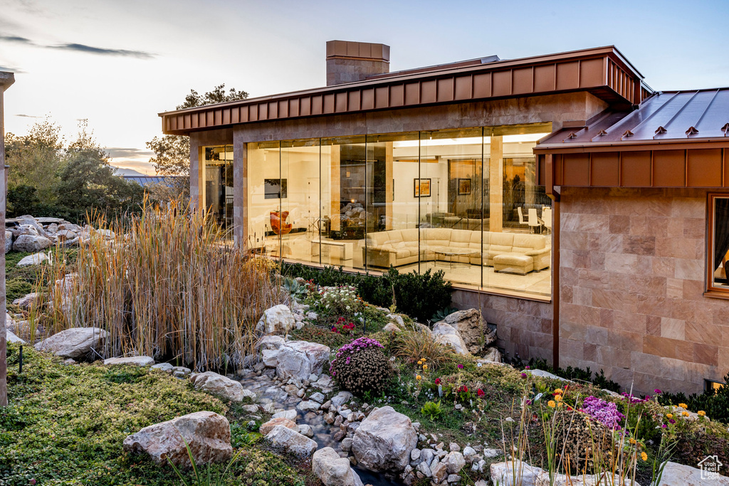View of home's exterior with a chimney, stone siding, and a standing seam roof