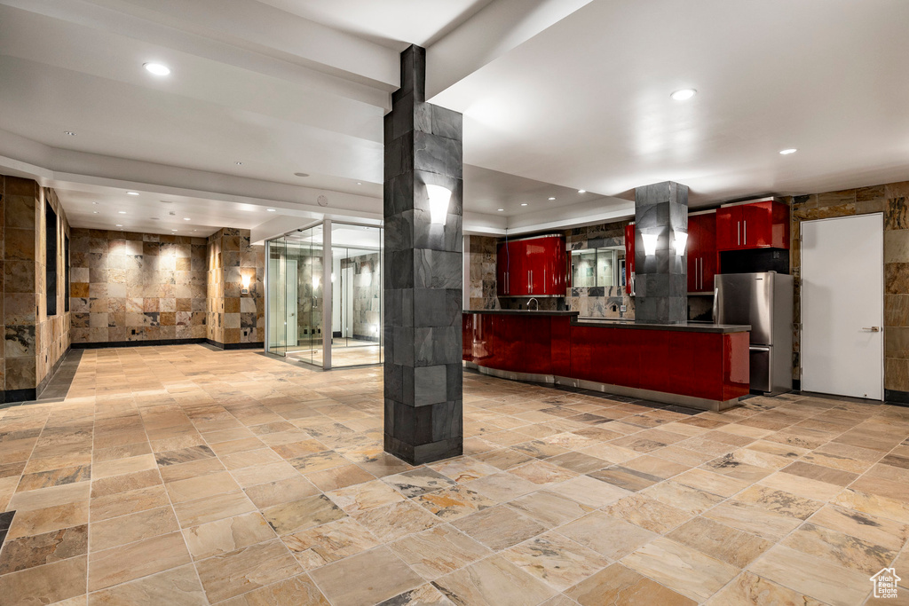 Kitchen with freestanding refrigerator, dark brown cabinets, recessed lighting, range hood, and dark countertops