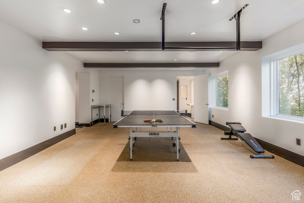 Rec room with beamed ceiling, light colored carpet, and a healthy amount of sunlight