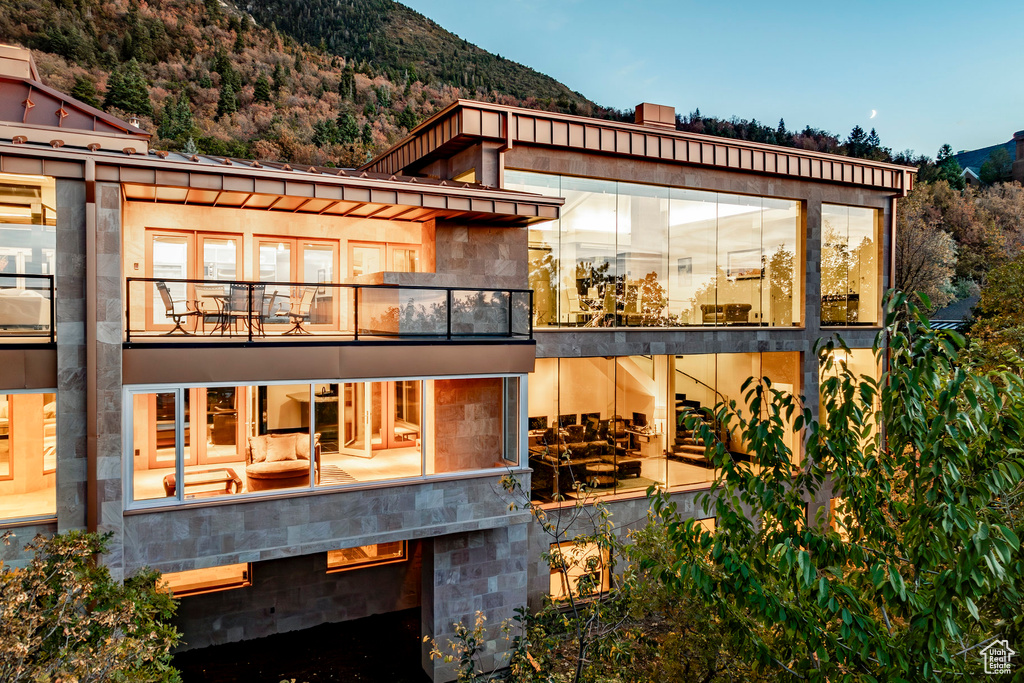 Rear view of property with a mountain view and a balcony