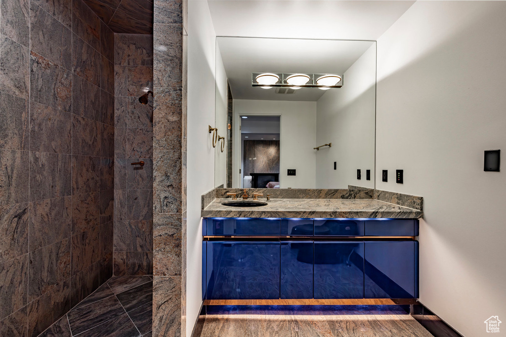 Bathroom with vanity, tiled shower, and baseboards