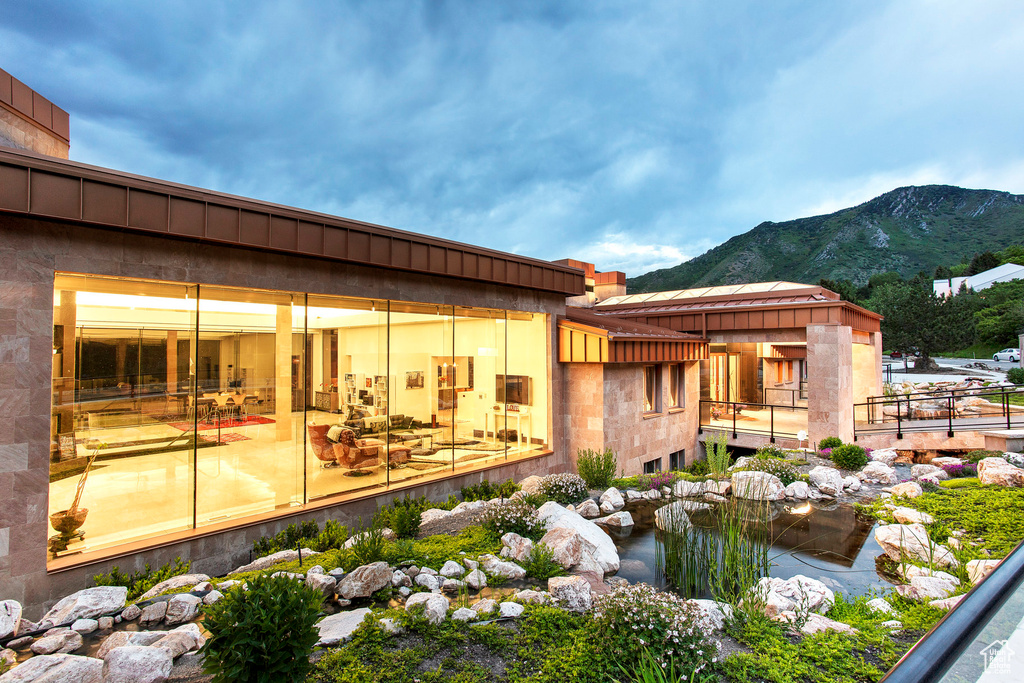 Back of house with a mountain view and a small pond