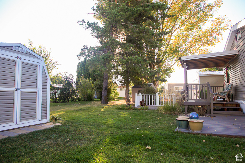 View of yard featuring a storage unit and a wooden deck