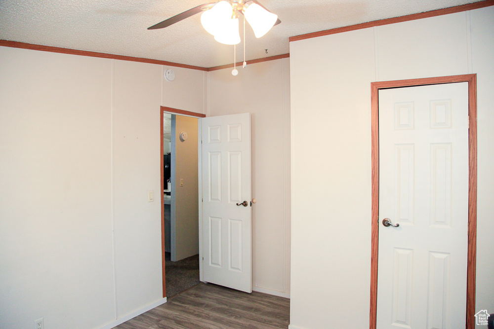 Spare room with a textured ceiling, ceiling fan, hardwood / wood-style floors, and crown molding