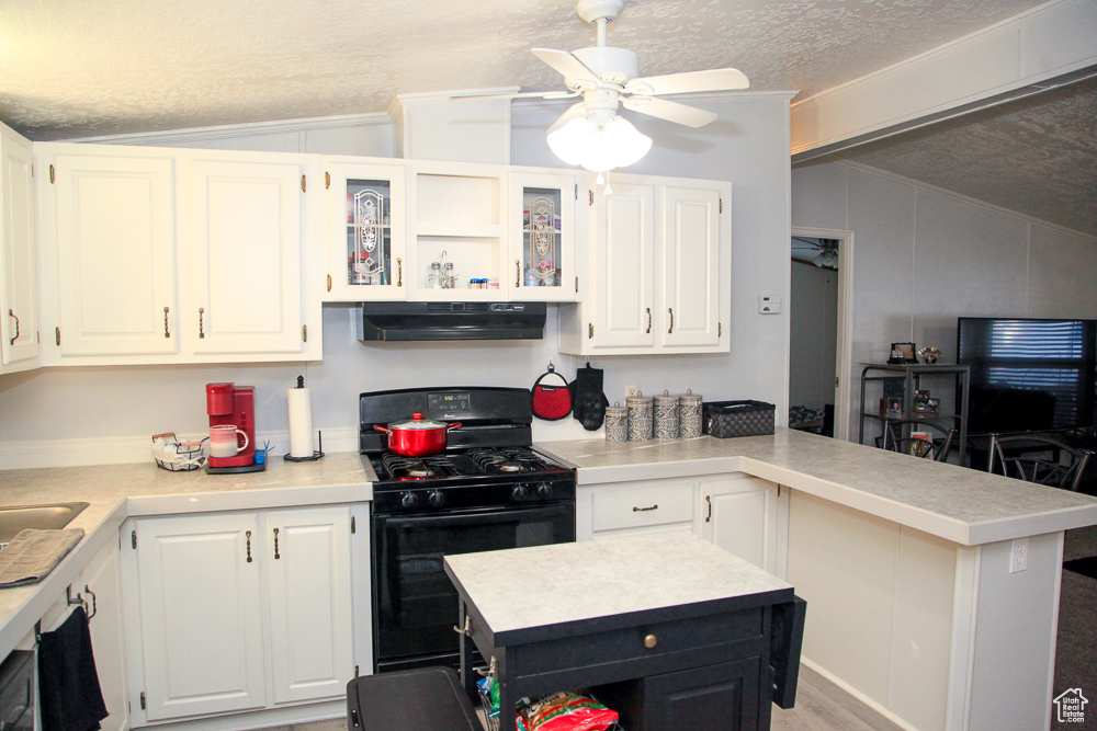 Kitchen with white cabinets, a textured ceiling, black range with gas cooktop, and range hood