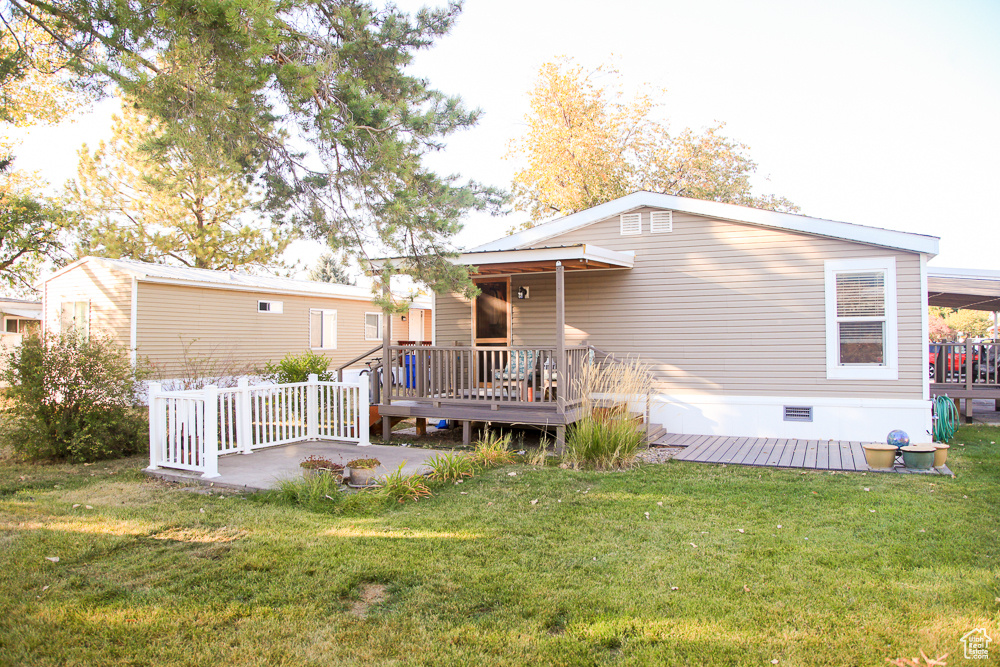 Back of property with a yard and a wooden deck