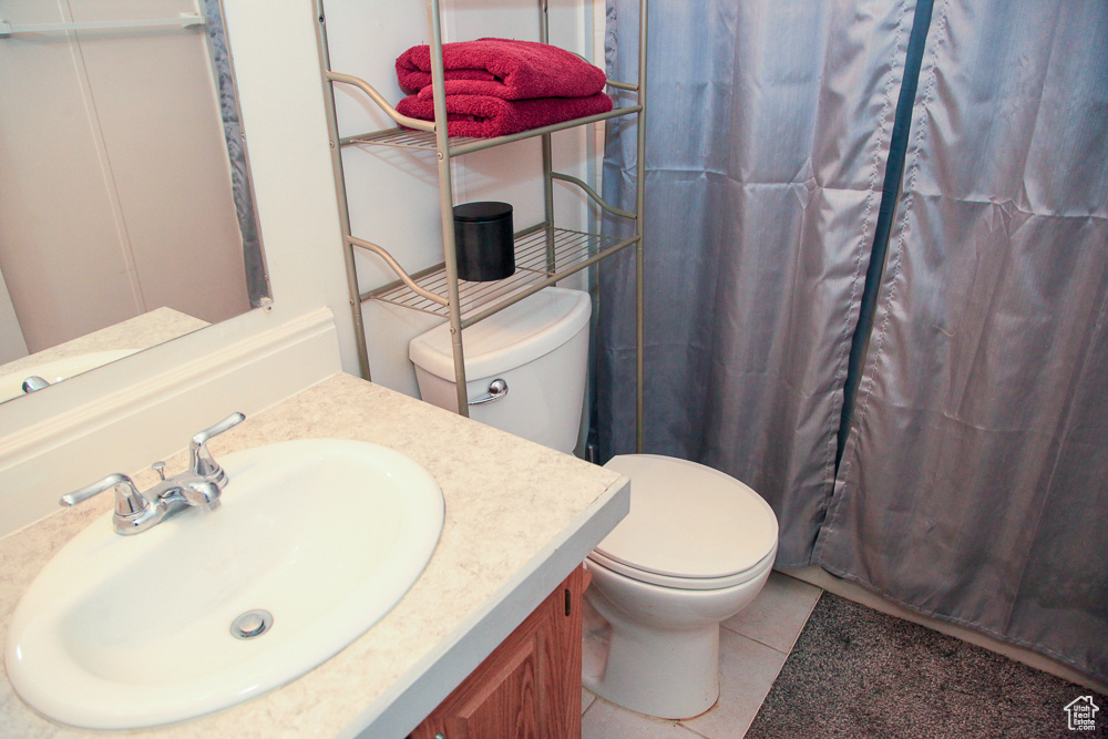 Bathroom with walk in shower, tile patterned flooring, vanity, and toilet