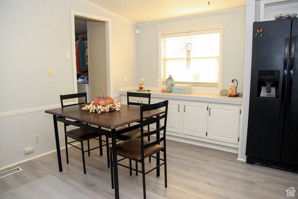 Dining space featuring light wood-type flooring, ornamental molding, and washer / dryer