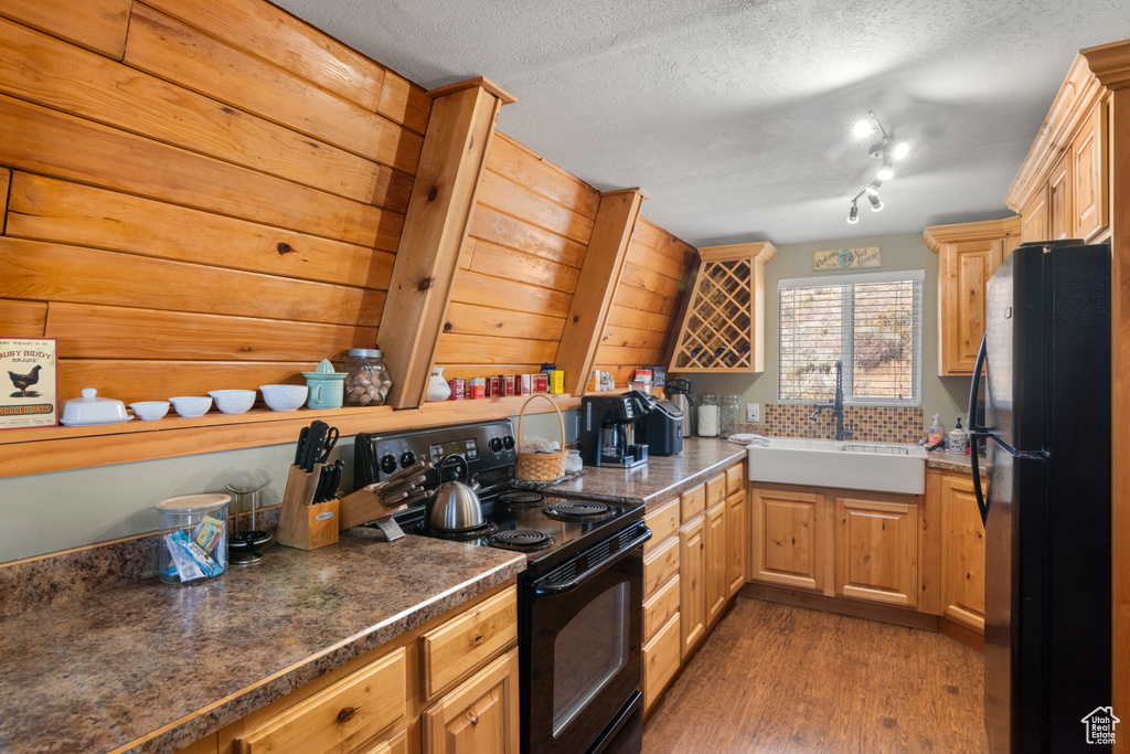 Kitchen featuring sink, dark wood-type flooring, a textured ceiling, and black appliances