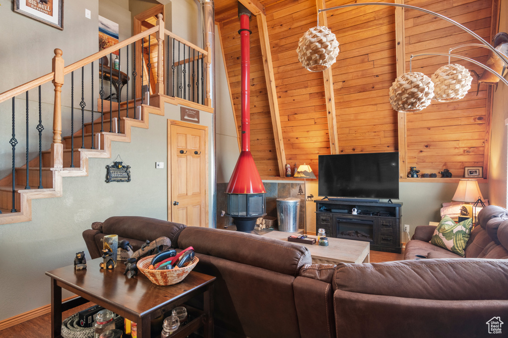 Living room featuring beam ceiling, wood-type flooring, wooden ceiling, a fireplace, and a towering ceiling