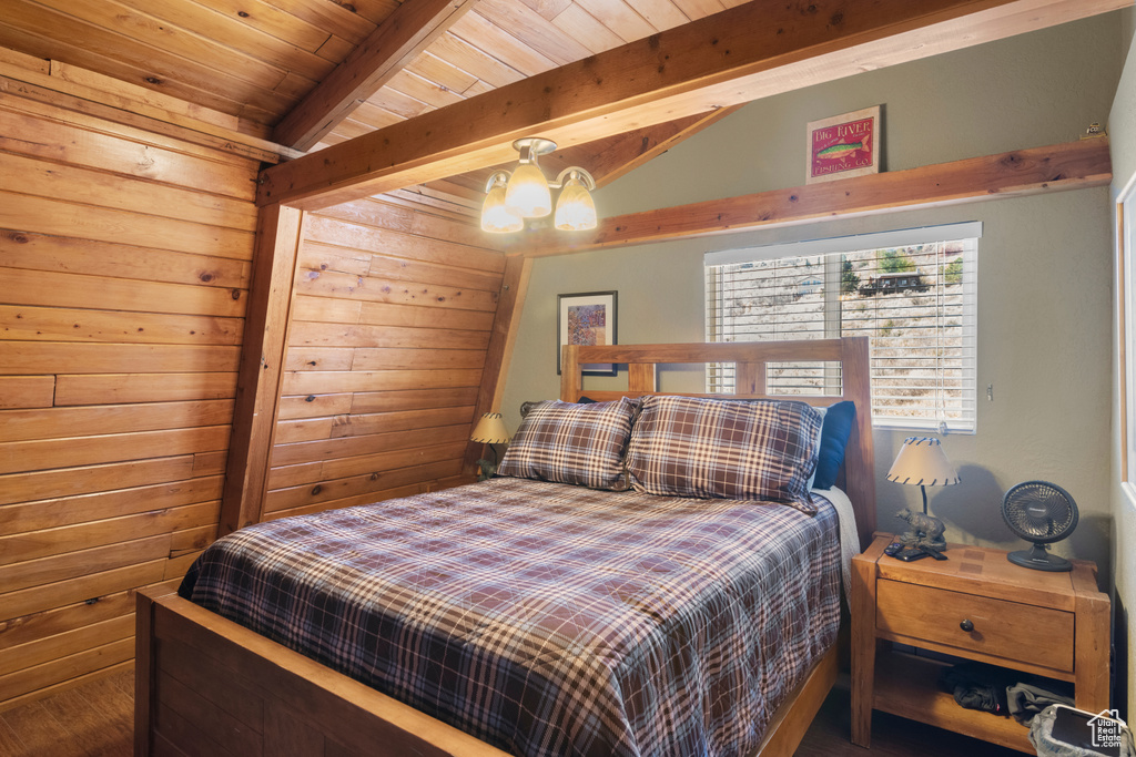 Bedroom with a notable chandelier, wood ceiling, and wood walls