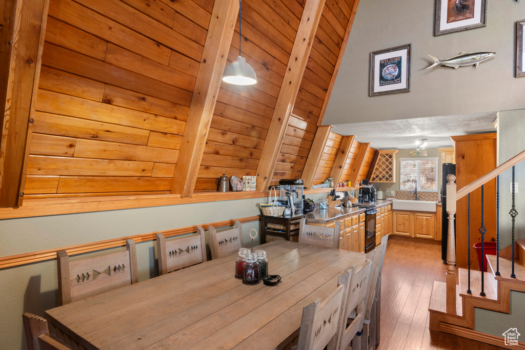 Dining area with light hardwood / wood-style flooring, lofted ceiling with beams, and wooden ceiling