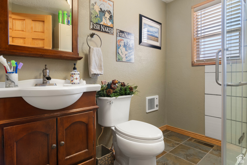 Bathroom with vanity, toilet, and a shower with shower door