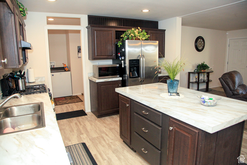 Kitchen featuring stainless steel appliances, light hardwood / wood-style floors, dark brown cabinetry, and sink