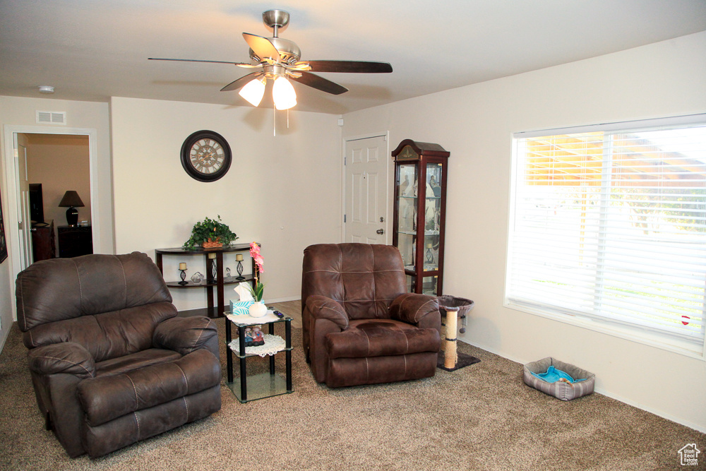 Living area with ceiling fan and carpet flooring