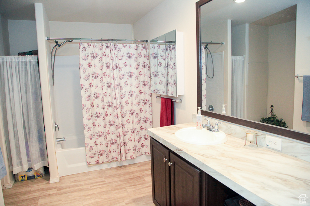 Bathroom with vanity, hardwood / wood-style floors, and shower / bath combo with shower curtain