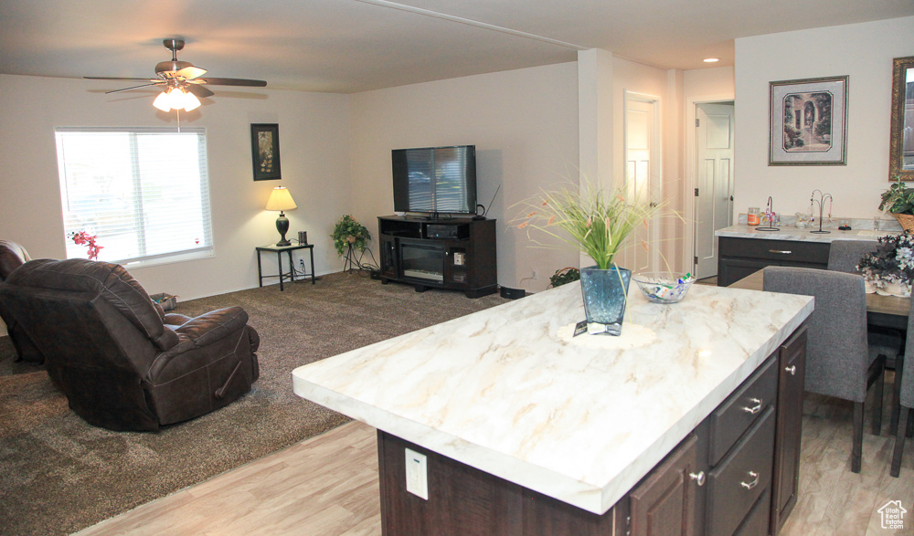 Kitchen with light wood-type flooring, a center island, dark brown cabinets, and ceiling fan