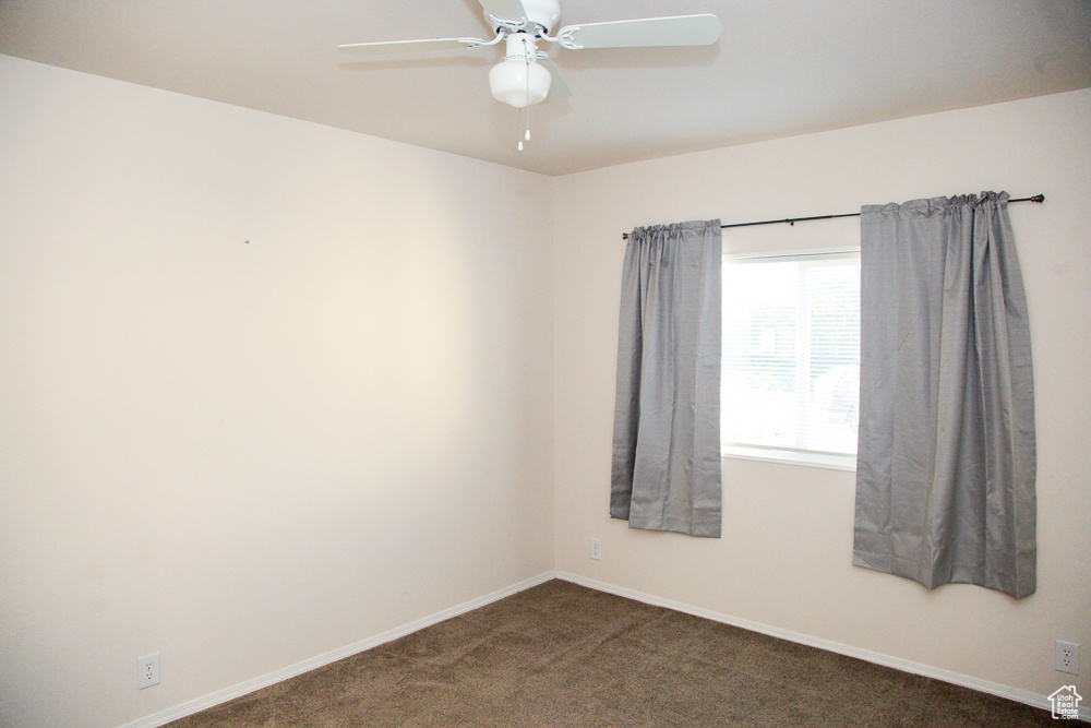 Unfurnished room with ceiling fan and dark carpet