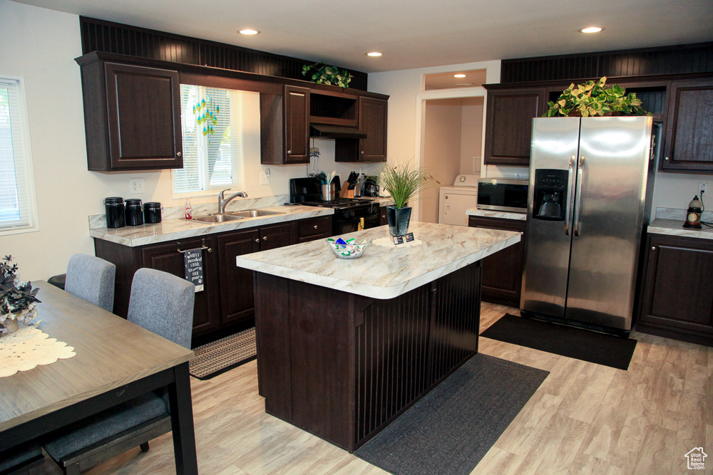 Kitchen with appliances with stainless steel finishes, light hardwood / wood-style floors, a center island, sink, and washing machine and clothes dryer