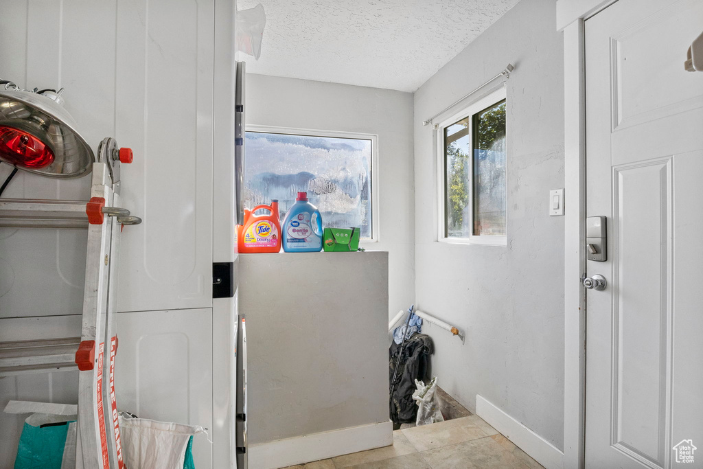 Washroom featuring a textured ceiling and light tile patterned floors