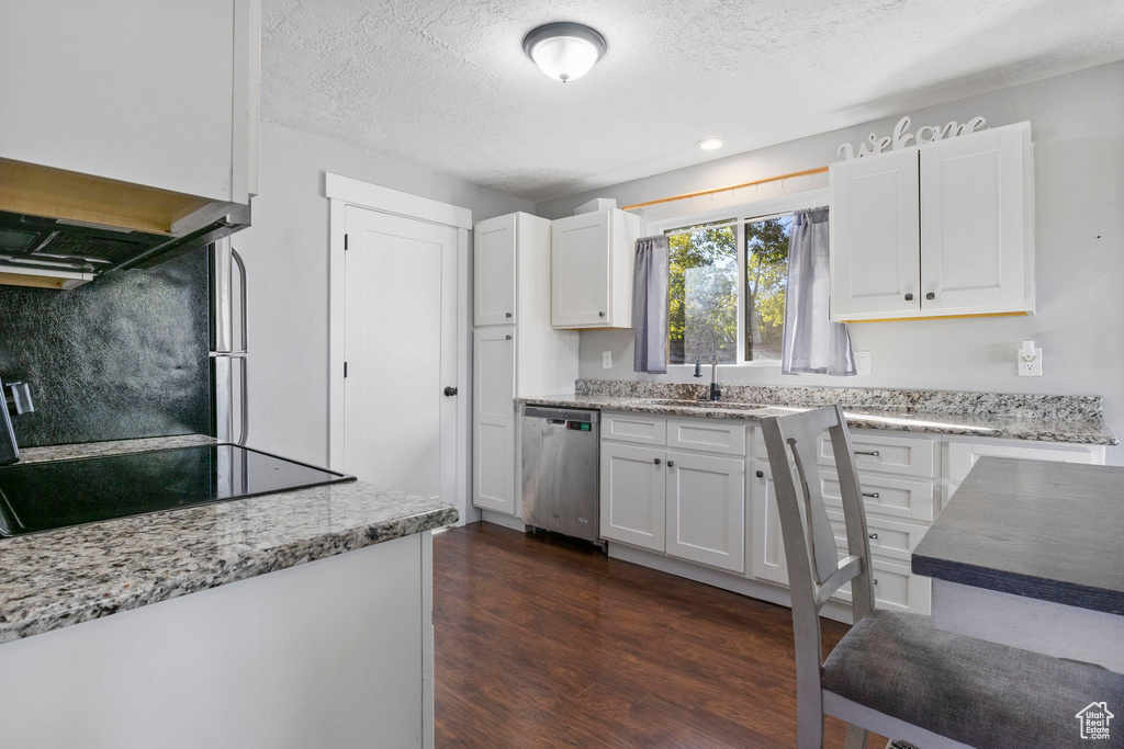 Kitchen featuring sink, a textured ceiling, dark wood-type flooring, white cabinetry, and dishwasher