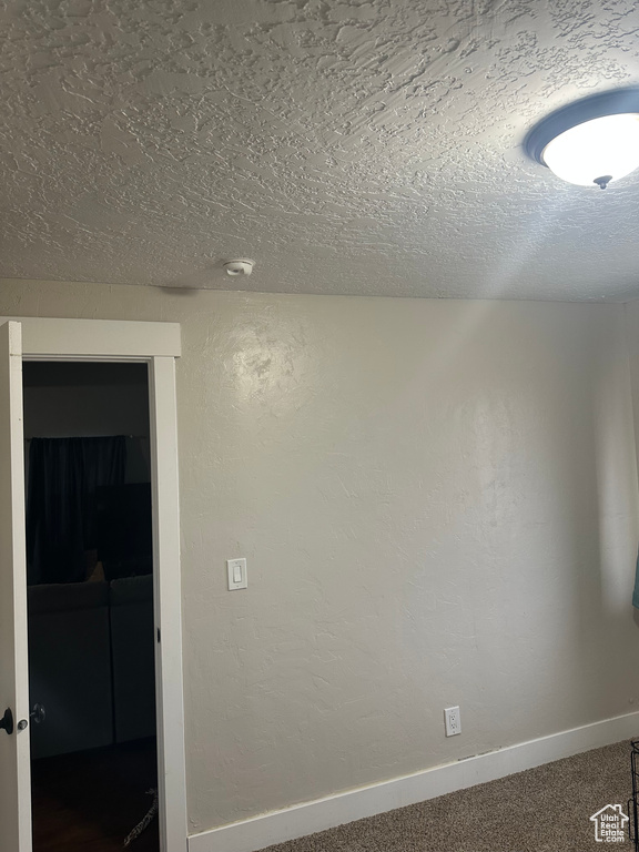 Carpeted empty room featuring a textured ceiling