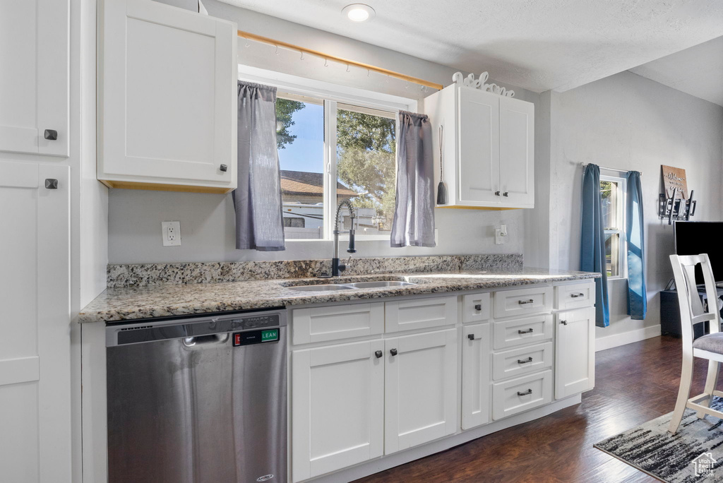 Kitchen with white cabinets, light stone countertops, stainless steel dishwasher, dark hardwood / wood-style floors, and sink