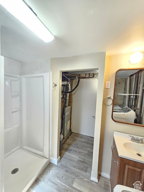 Bathroom with wood-type flooring, separate washer and dryer, walk in shower, and vanity