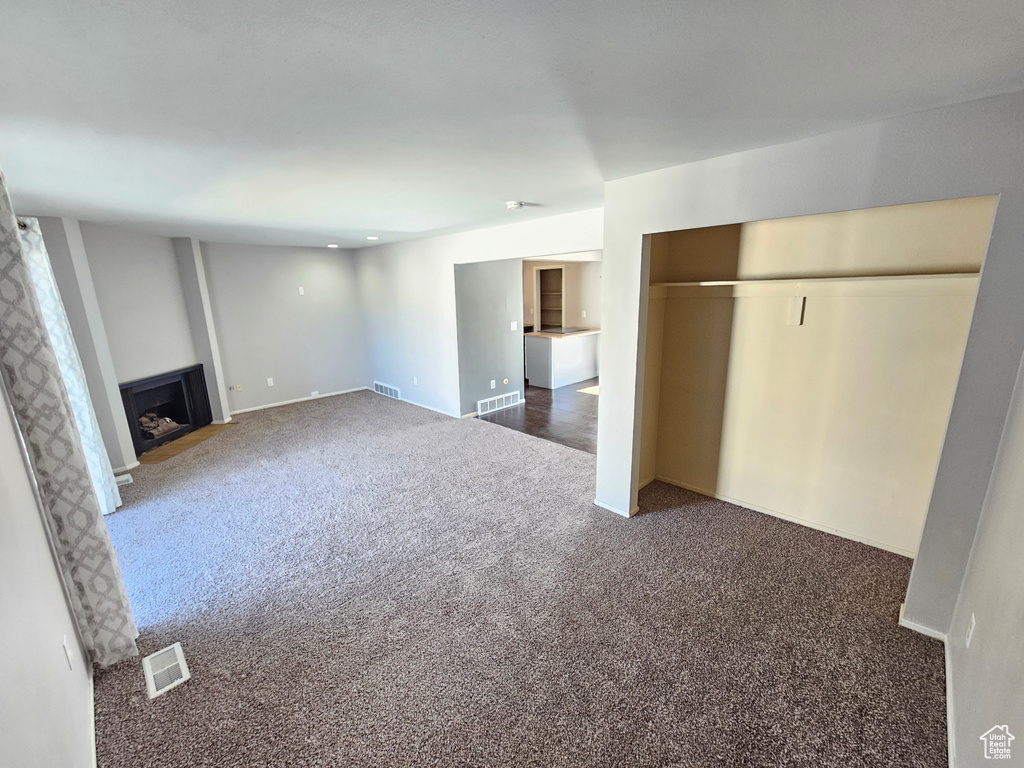 Unfurnished living room featuring dark carpet