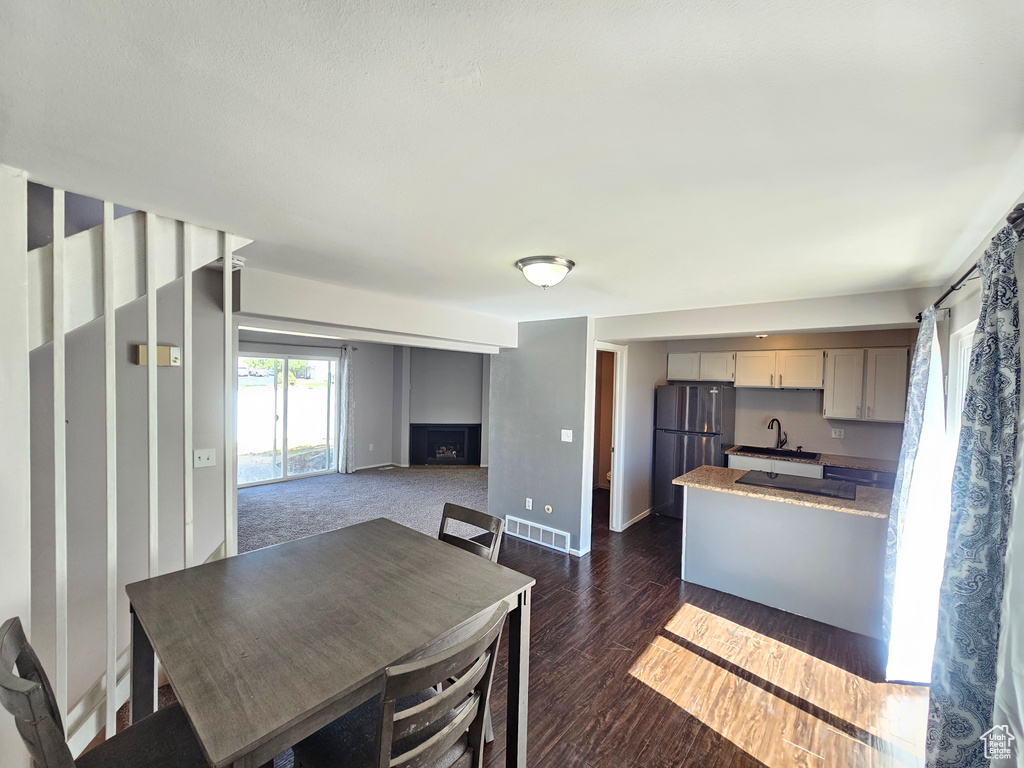 Kitchen featuring stainless steel refrigerator, a fireplace, sink, and dark wood-type flooring