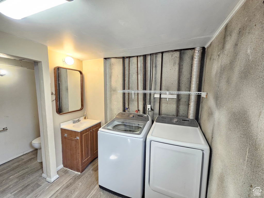 Laundry area featuring light hardwood / wood-style flooring, sink, and washing machine and clothes dryer