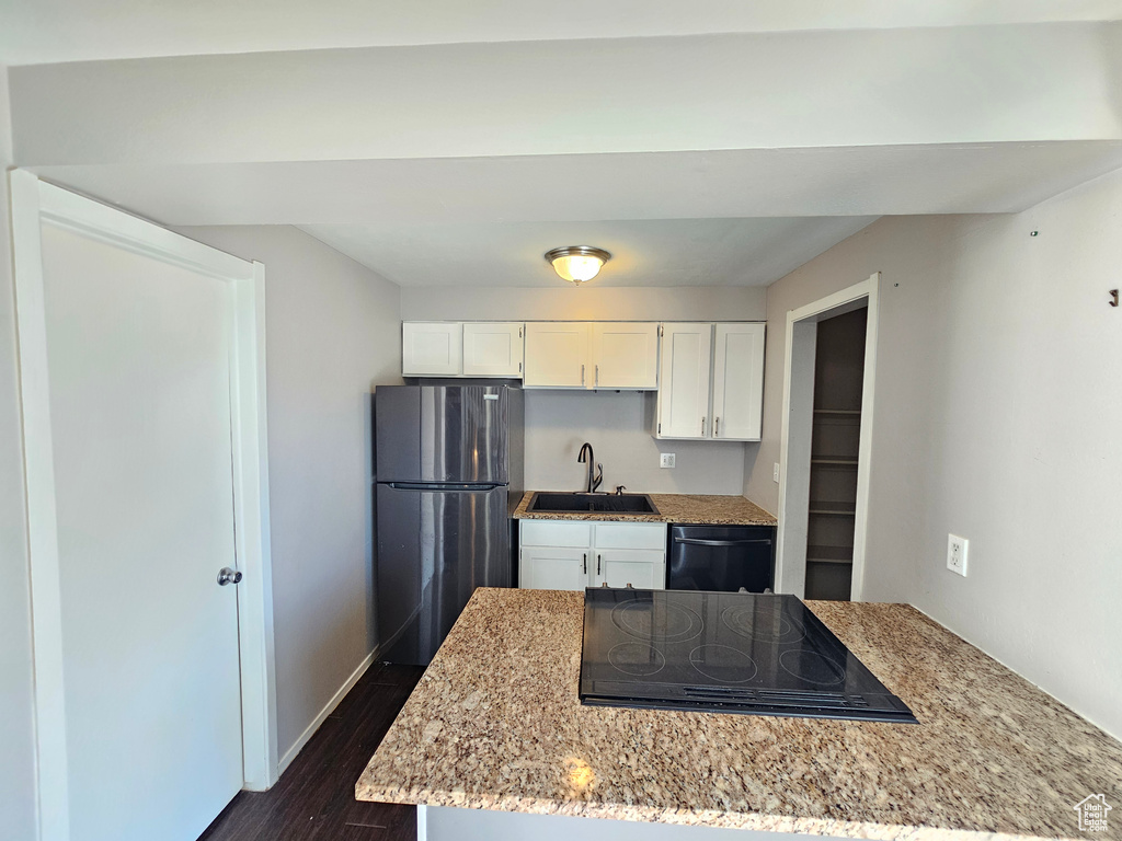 Kitchen with white cabinetry, light stone counters, dark hardwood / wood-style flooring, stainless steel appliances, and sink