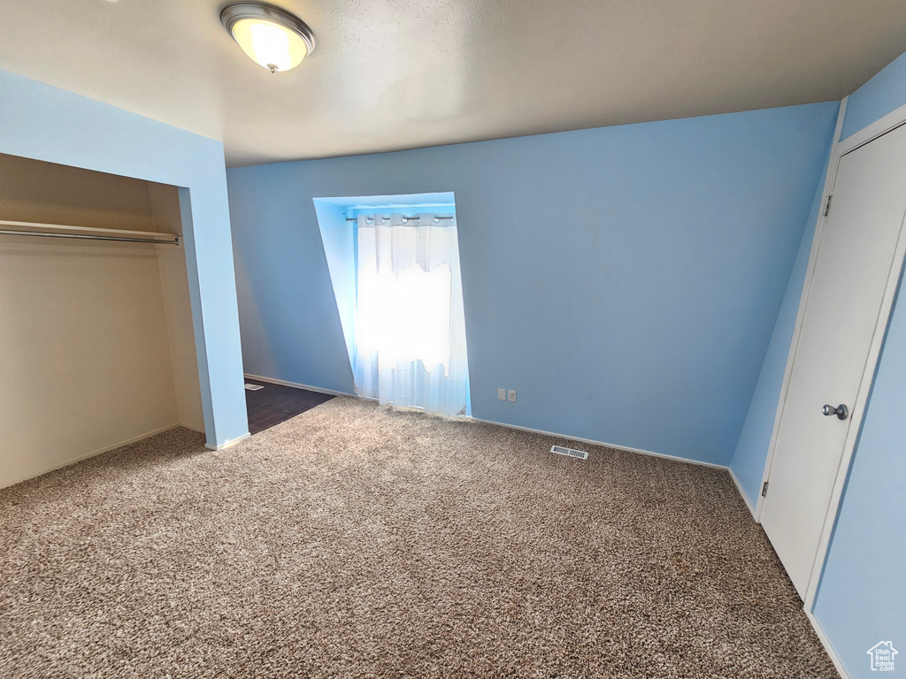 Unfurnished bedroom with dark carpet and a closet