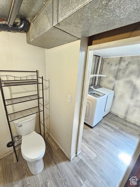 Bathroom with toilet, hardwood / wood-style floors, and washer and dryer