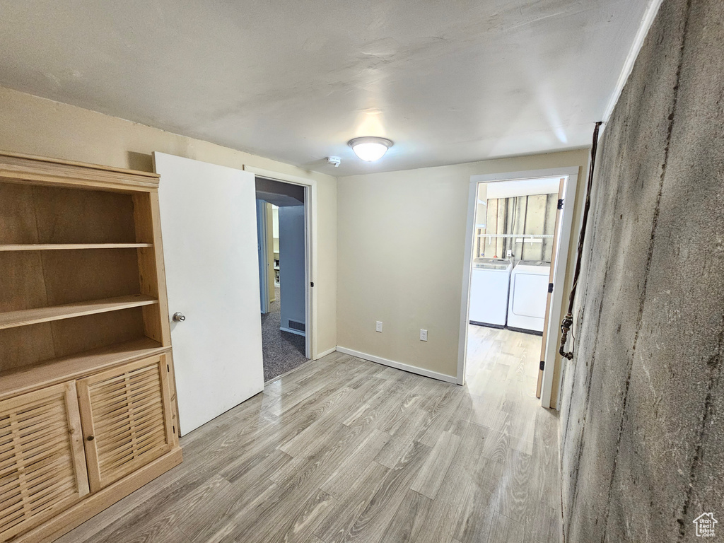 Empty room with separate washer and dryer and light wood-type flooring