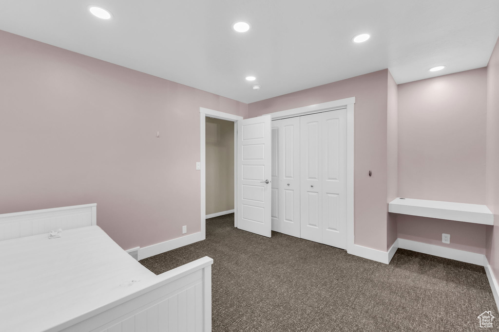 Bedroom with a closet and dark colored carpet