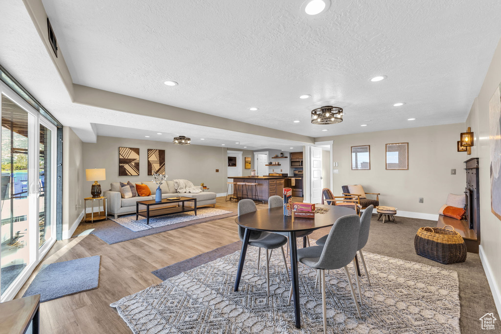 Dining area featuring an inviting chandelier, a textured ceiling, and light hardwood / wood-style floors