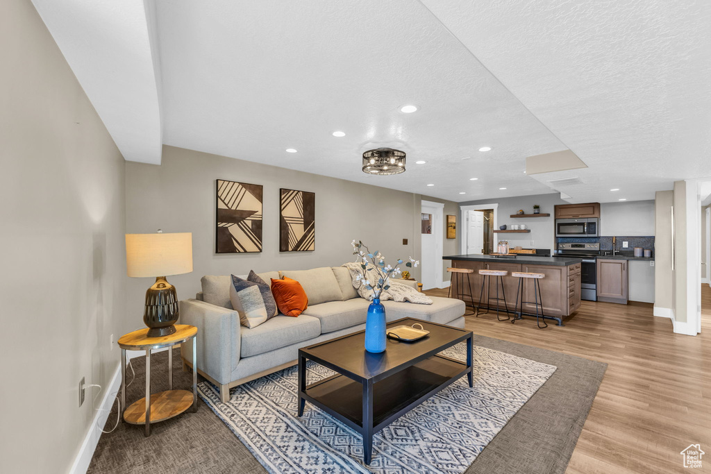 Living room with a textured ceiling, sink, and light hardwood / wood-style floors