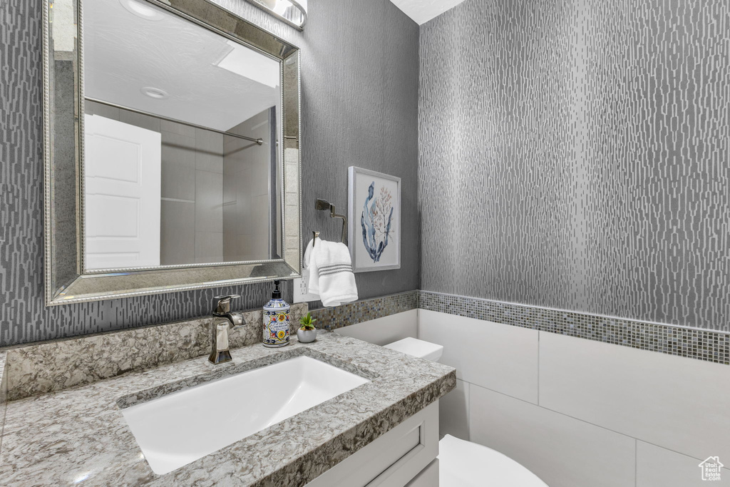 Bathroom featuring tiled shower, vanity, and toilet